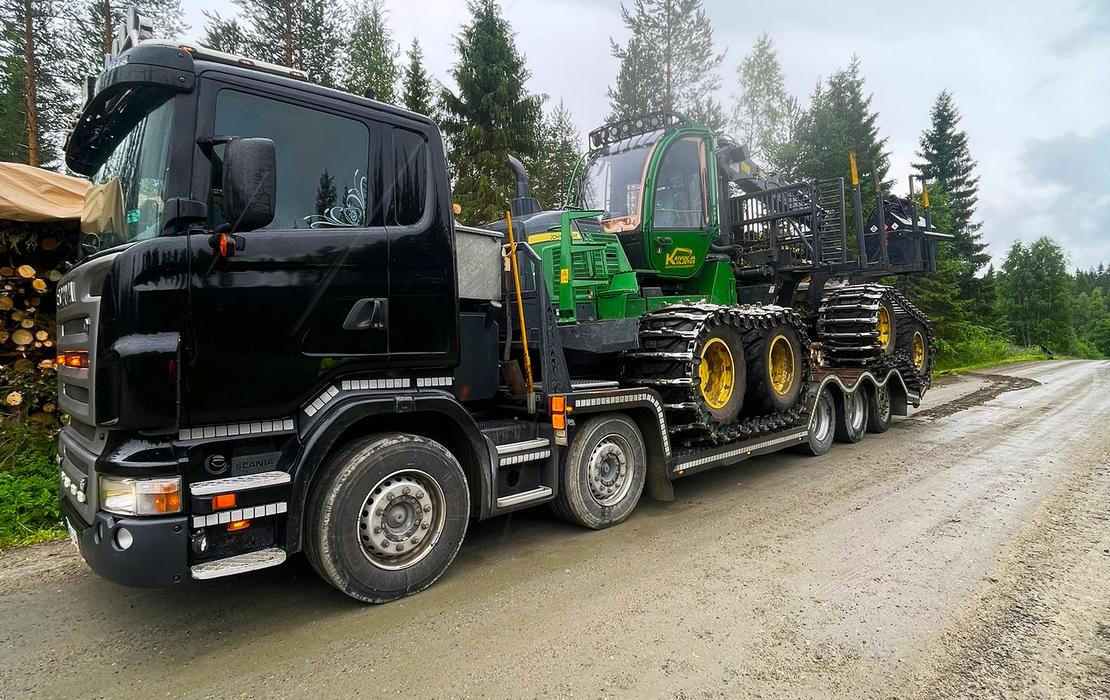 Mets&auml;kone kuljetettavana lavettirekalla ty&ouml;maalle soratiet&auml; pitkin.